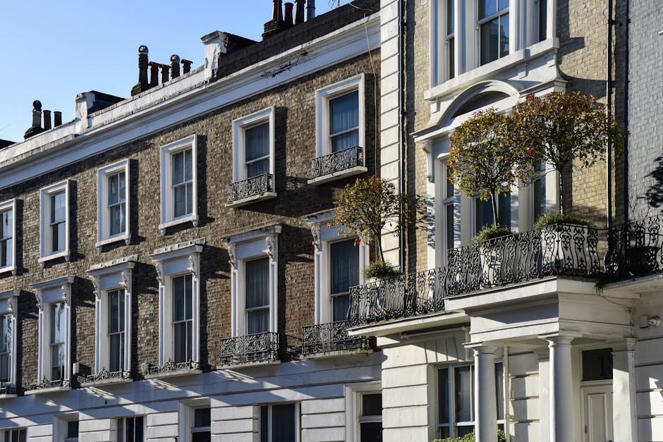 The image shows a row of traditional white Victorian-style terraced houses with ornate architectural details, including decorative cornices and balustrade balconies on the upper floors. The buildings 